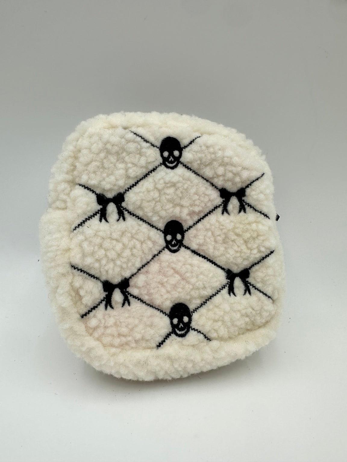 Cream textured travel pouch with black embroidered skulls and bows